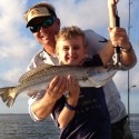 Young customer holding trout caught while fishing with Daytona Beach fishing guide, Capt. Mike Mann